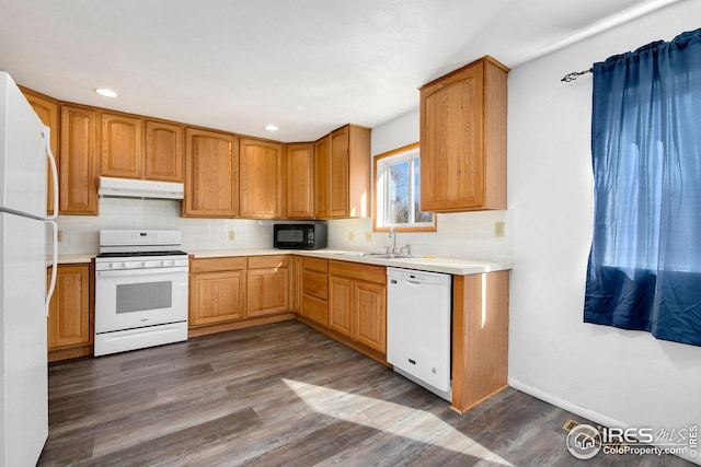 kitchen featuring white appliances, under cabinet range hood, a sink, tasteful backsplash, and light countertops