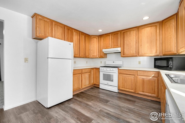 kitchen with white appliances, under cabinet range hood, dark wood finished floors, light countertops, and backsplash