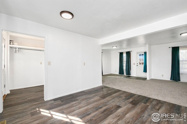unfurnished living room featuring dark wood-style floors and baseboards