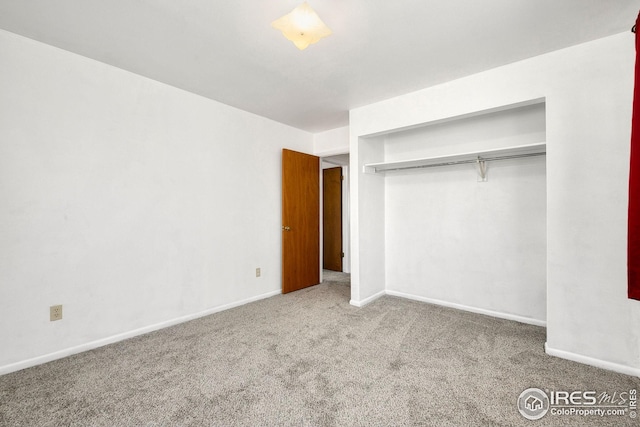 unfurnished bedroom featuring carpet floors, baseboards, and a closet