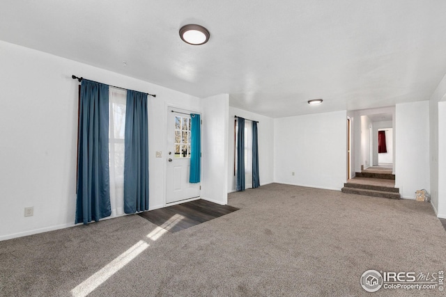 spare room with carpet floors, baseboards, and stairs