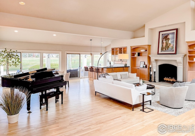 living area with light wood-style floors, lofted ceiling, a fireplace, and recessed lighting