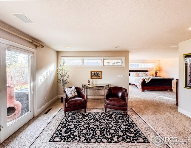 living area with carpet flooring, a textured ceiling, and baseboards