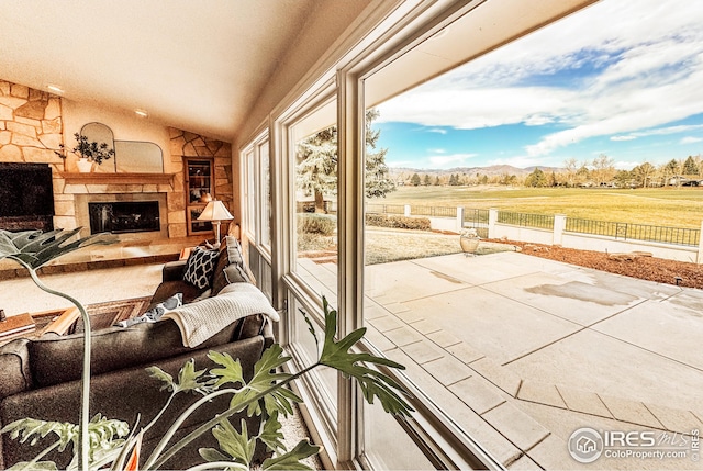 living area featuring lofted ceiling, a mountain view, and a stone fireplace