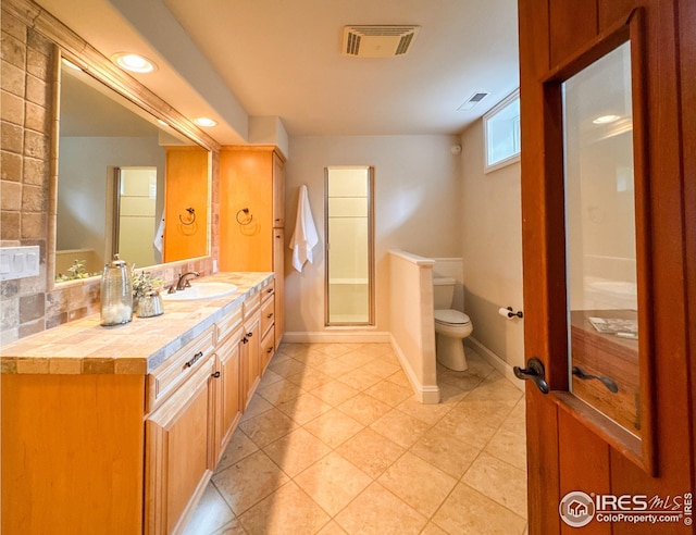 bathroom featuring toilet, an enclosed shower, vanity, tile patterned floors, and baseboards