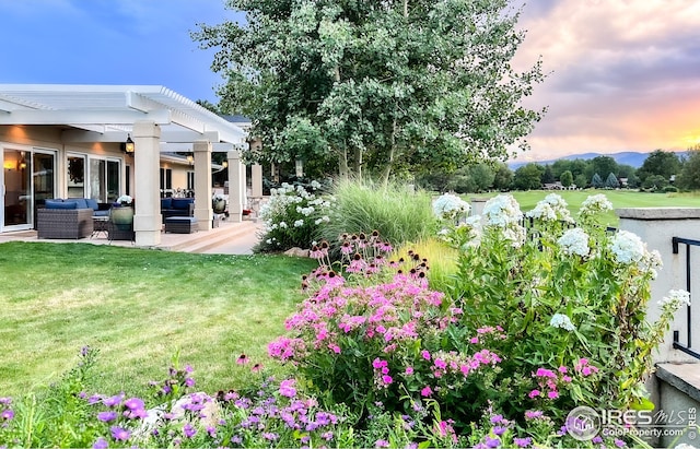 yard at dusk with an outdoor hangout area, a pergola, a yard, and a patio