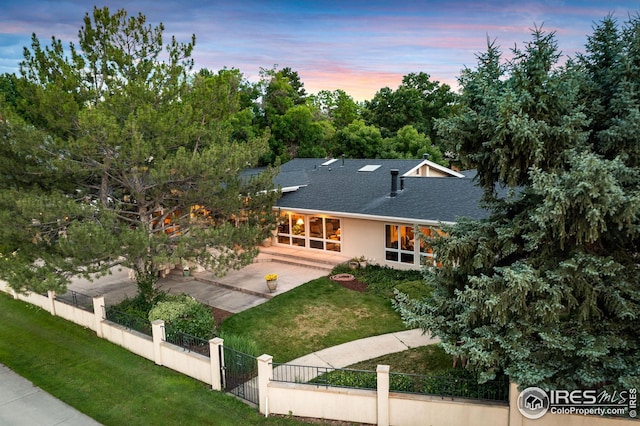 view of front of house featuring a shingled roof, a patio area, and a gate