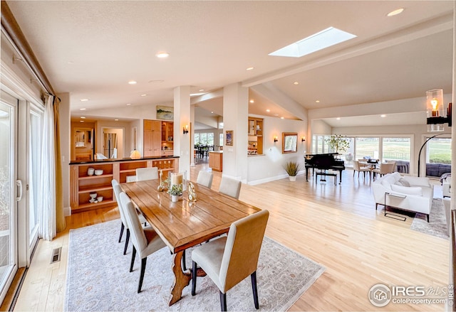 dining room featuring light wood-type flooring, lofted ceiling, a skylight, baseboards, and recessed lighting