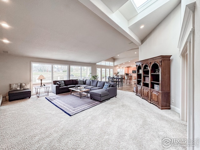 living area with carpet flooring, recessed lighting, a skylight, a towering ceiling, and baseboards