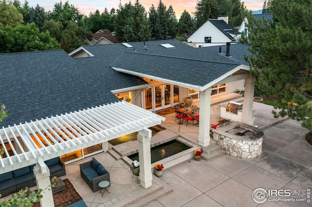 back of property featuring roof with shingles, a patio area, french doors, an outdoor living space with a fire pit, and exterior kitchen
