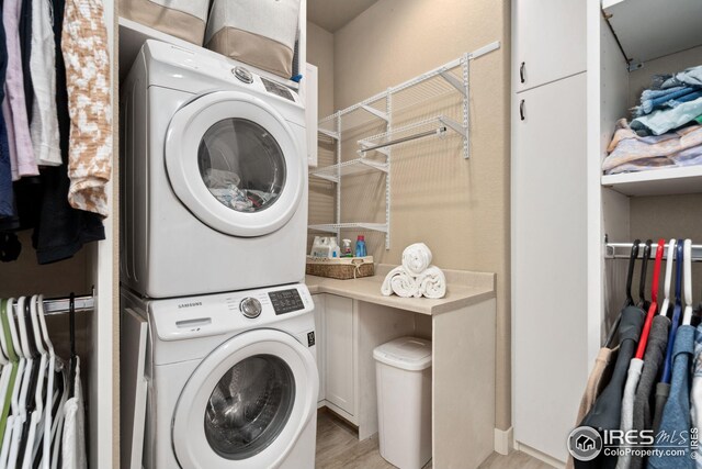 clothes washing area with stacked washer and dryer, laundry area, and light wood-style flooring