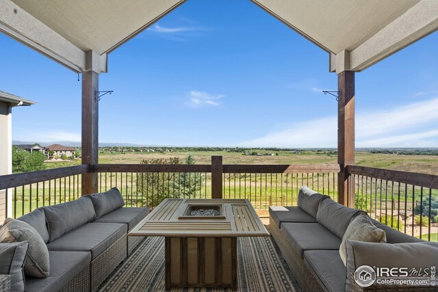 wooden deck with a rural view and an outdoor living space with a fire pit