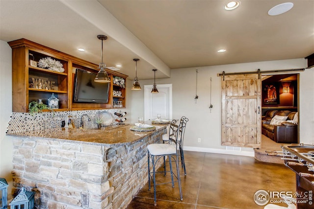 bar featuring a barn door, recessed lighting, wet bar, tasteful backsplash, and finished concrete flooring