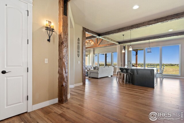 interior space with beam ceiling, a sink, baseboards, recessed lighting, and wood finished floors
