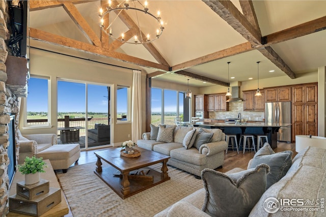 living room featuring lofted ceiling with beams, light wood-style floors, and a chandelier