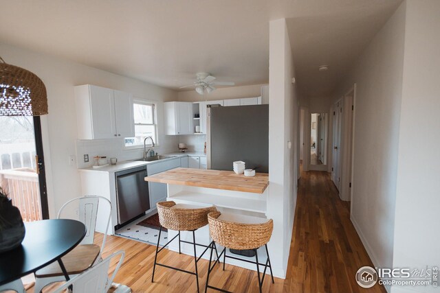 kitchen with white cabinetry, decorative backsplash, a sink, a ceiling fan, and appliances with stainless steel finishes