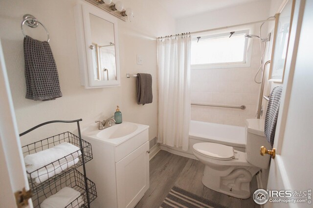 bathroom featuring toilet, shower / bath combo with shower curtain, vanity, and wood finished floors