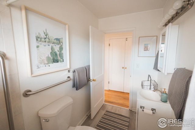 bathroom with toilet, vanity, and wood finished floors