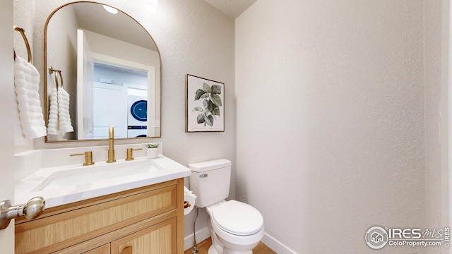 bathroom featuring vanity, toilet, and a textured wall