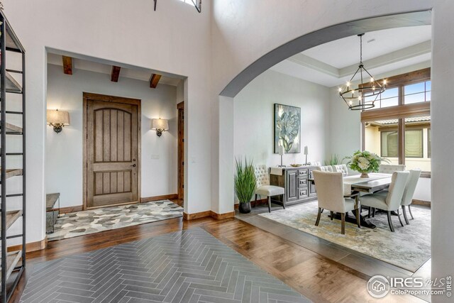 3865 Valley Crest Dr, Timnath, CO 80547 - entrance foyer featuring a high ceiling, wood finished floors, baseboards, arched walkways, and an inviting chandelier