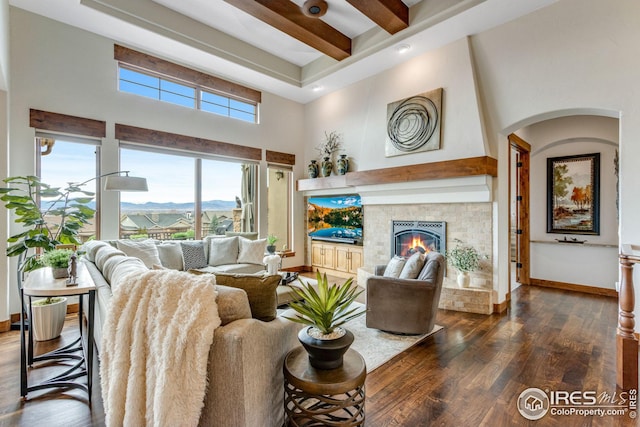3865 Valley Crest Dr, Timnath, CO 80547 - living room featuring a lit fireplace, baseboards, a high ceiling, beam ceiling, and wood finished floors
