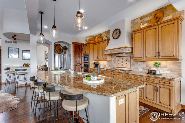 3865 Valley Crest Dr, Timnath, CO 80547 - kitchen featuring a spacious island, backsplash, appliances with stainless steel finishes, premium range hood, and visible vents