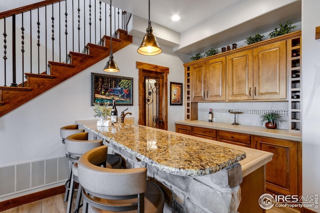 3865 Valley Crest Dr, Timnath, CO 80547 - kitchen with an island with sink, visible vents, decorative light fixtures, light wood-style floors, and decorative backsplash