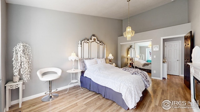 bedroom with baseboards, an inviting chandelier, and light wood-style floors