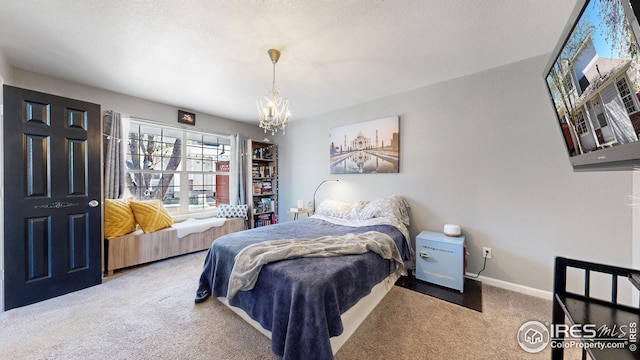 carpeted bedroom with baseboards, a textured ceiling, and a chandelier