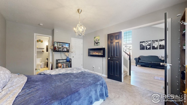 carpeted bedroom with a notable chandelier, connected bathroom, and baseboards