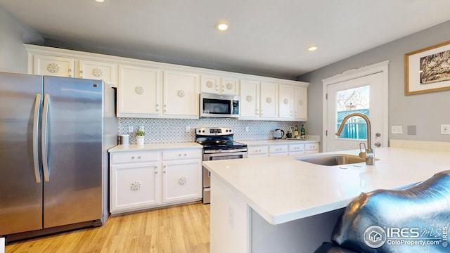 kitchen featuring a sink, a breakfast bar area, a peninsula, stainless steel appliances, and white cabinets