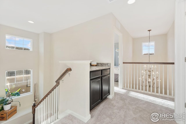 hall featuring light carpet, an upstairs landing, recessed lighting, and an inviting chandelier