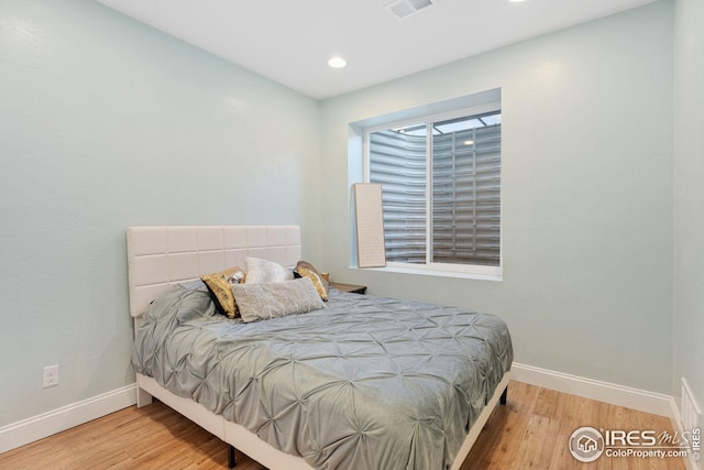 bedroom featuring baseboards, visible vents, and wood finished floors
