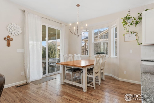 dining space featuring baseboards, visible vents, a notable chandelier, and light wood-style flooring