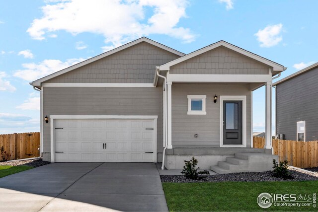 view of front facade with driveway, a garage, and fence