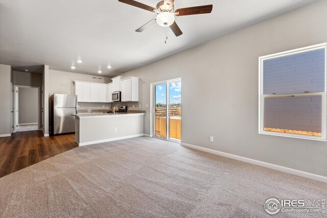 kitchen with open floor plan, white cabinetry, dark colored carpet, stainless steel appliances, and a ceiling fan