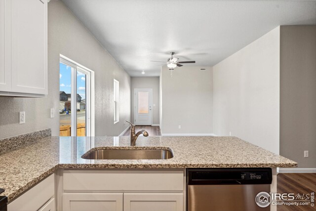 kitchen with white cabinetry, stainless steel dishwasher, a sink, light stone counters, and a ceiling fan