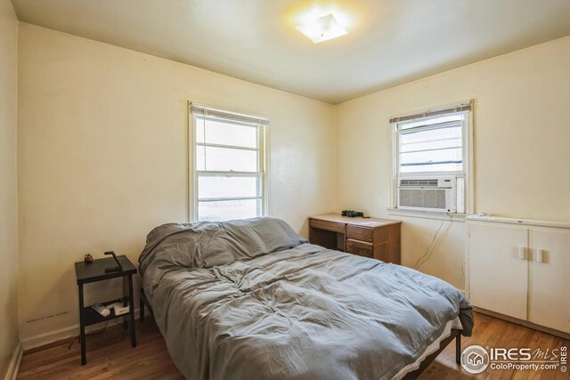 bedroom with baseboards, cooling unit, and wood finished floors