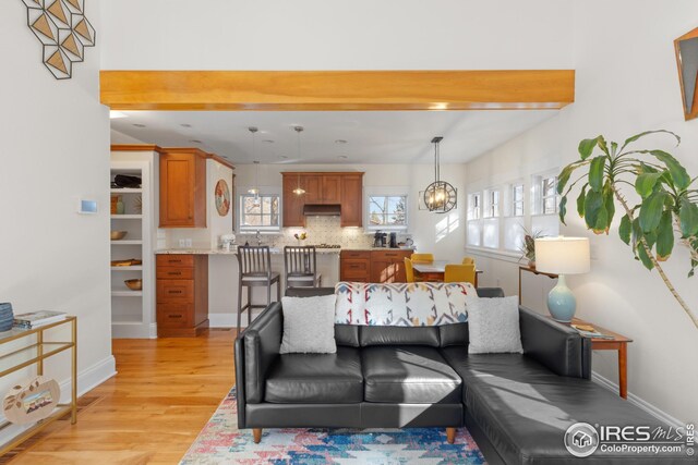 1016 Katy Ln, Longmont, CO 80504 - living area featuring light wood finished floors, baseboards, and an inviting chandelier