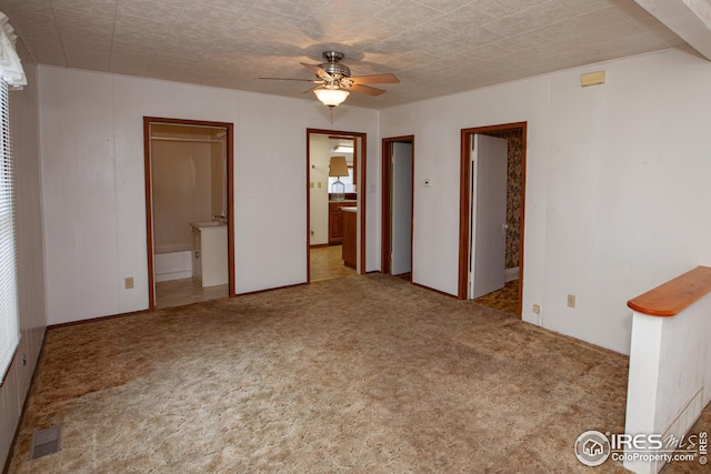 carpeted spare room with visible vents and ceiling fan
