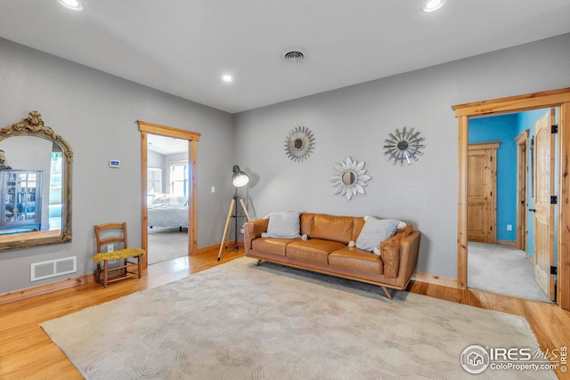 living room with recessed lighting, visible vents, and wood finished floors