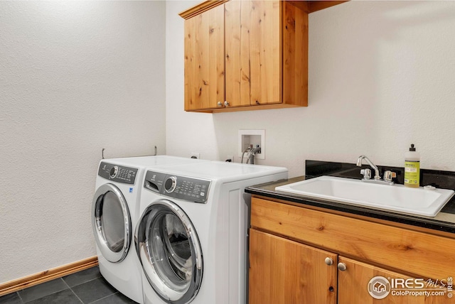 laundry area featuring a sink, baseboards, separate washer and dryer, cabinet space, and dark tile patterned flooring