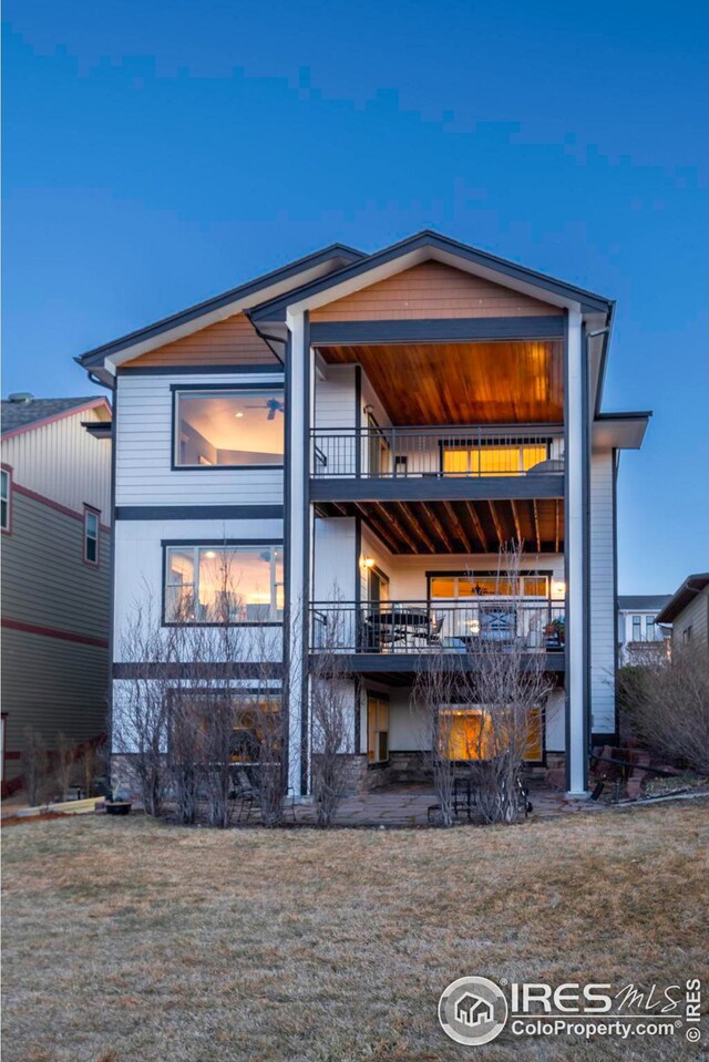 rear view of house featuring a lawn and a balcony