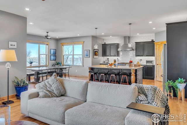 living area with recessed lighting, ceiling fan, and light wood-style floors