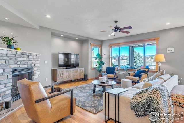 living area with recessed lighting, ceiling fan, wood finished floors, and a fireplace