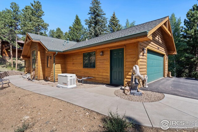 cabin featuring aphalt driveway and roof with shingles