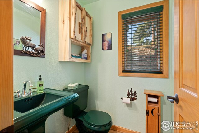 bathroom with baseboards, toilet, and a sink