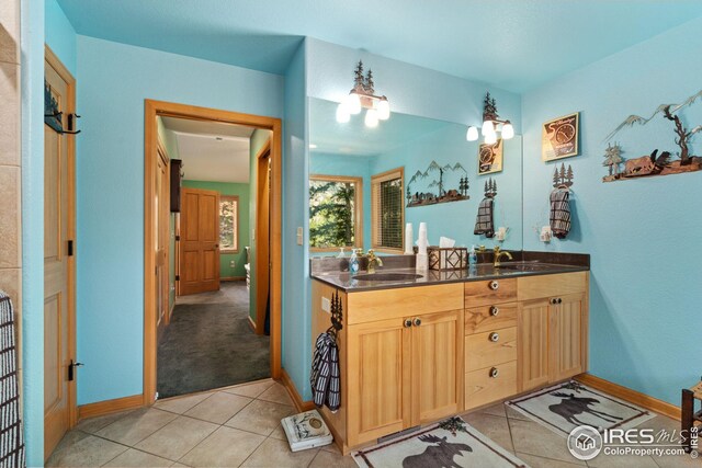 full bathroom featuring baseboards, double vanity, a sink, and tile patterned flooring