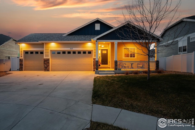 craftsman inspired home with concrete driveway, fence, board and batten siding, covered porch, and a garage