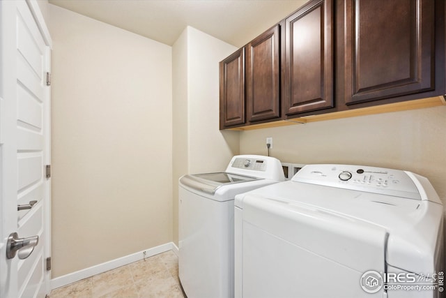 washroom with light tile patterned floors, washer and clothes dryer, cabinet space, and baseboards